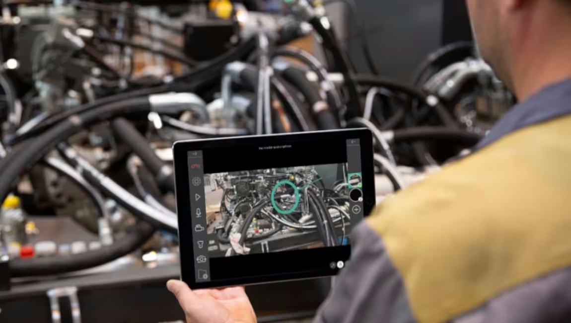 Technician holding a tablet over an open tractor wiring harness